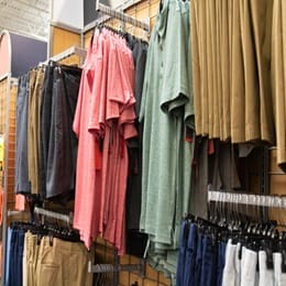 Retail display of men's casual clothing including polo shirts and khaki shorts arranged on racks in a store