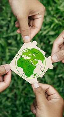 Multiple hands assembling puzzle pieces that form a green Earth graphic, symbolizing Cornerstone Systems' commitment to sustainability in Memphis